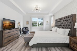 Una camera da letto moderna con un letto grande, una televisione su una cassettiera in legno e una finestra con persiane.