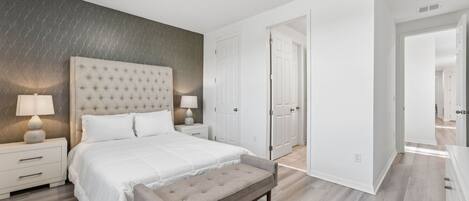 A bedroom with a large bed, bedside tables, a bench, and a wardrobe.