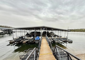 Ein vertäutes Boot mit einer überdachten Konstruktion, einem hölzernen Steg und ruhigem Wasser.