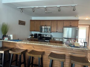 A kitchen with wooden cabinets, stainless steel appliances, bar stools, and a countertop with various items. - 
Penthouse with an open balcony. Greatest Location, Boat Slip upon request only (Osage Beach)