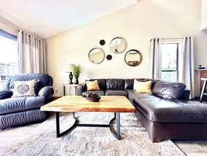 Ein Wohnzimmer mit Sofa, Sessel, Couchtisch und dekorativen Spiegeln an der Wand.