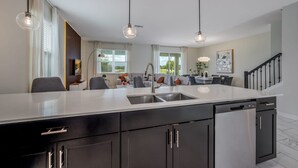 Een moderne keuken met een centraal eiland, zwarte kastjes en hanglampen.