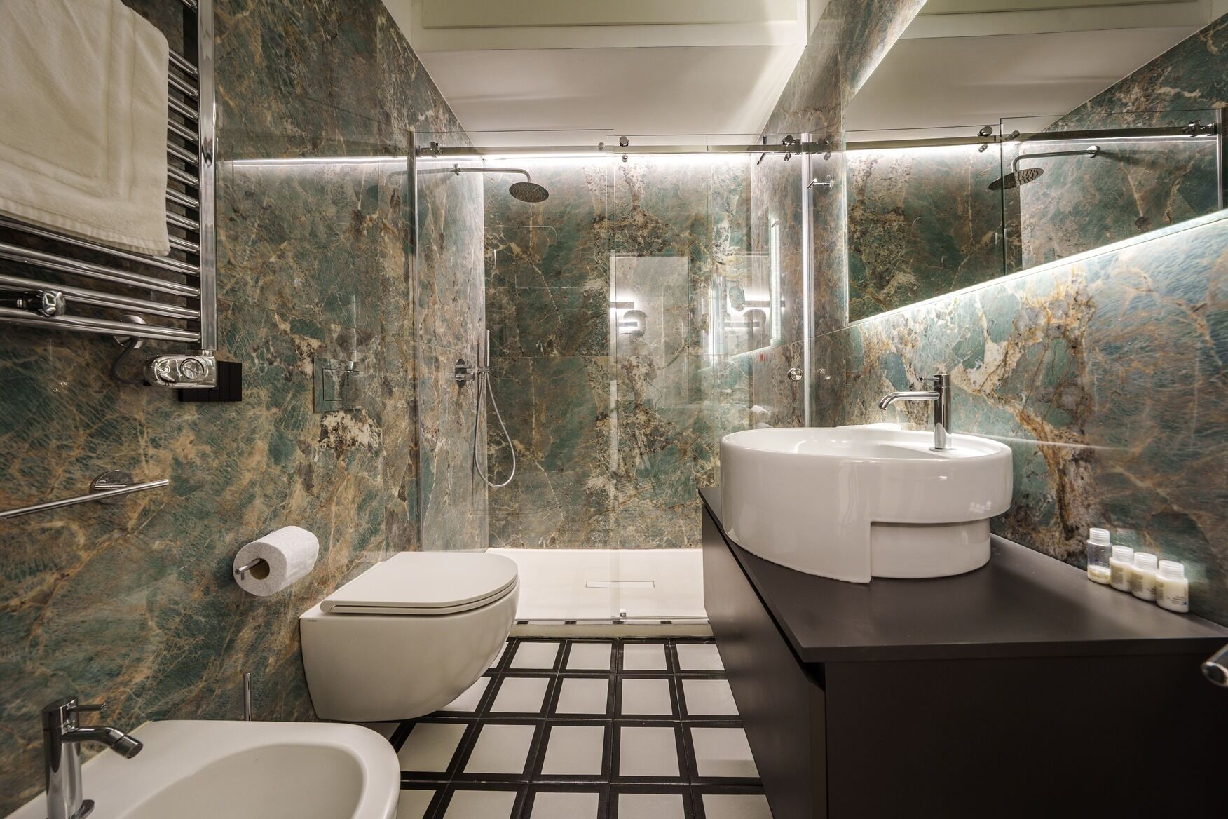 A modern bathroom with a shower, toilet, sink, and a marble wall.