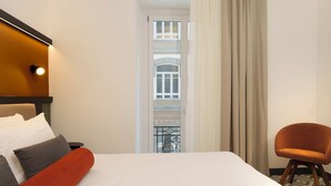 A hotel room with a bed, a chair, a window with curtains, and a view of a building. - La Dimora del Corso 35 (Naples)