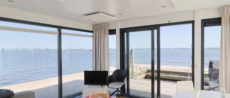 Una habitación moderna con un gran ventanal, un televisor de pantalla plana, una mesa de comedor y un sofá.