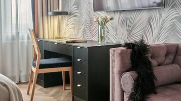 A modern room with a desk, a chair, a sofa, and a flat-screen TV mounted on the wall.