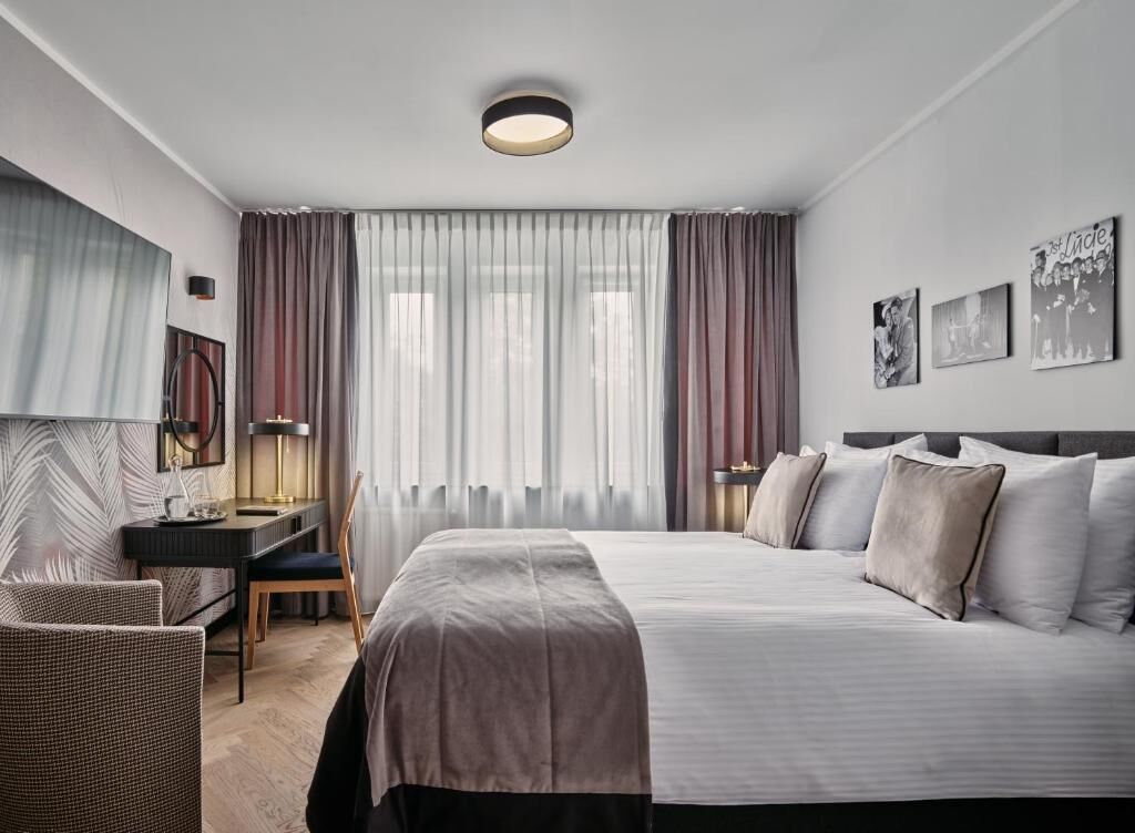 A hotel room with a large bed, a desk, a chair, and a television.