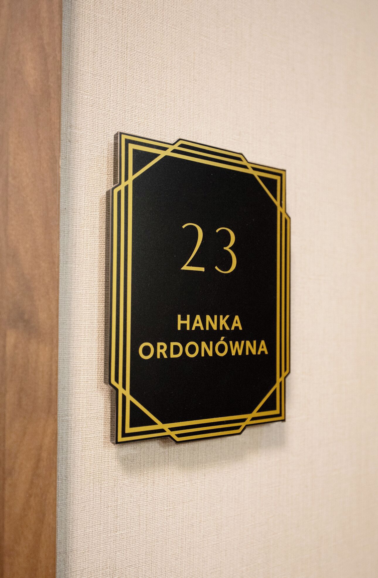A black and gold sign with the number 23 and the name "Hanka Ordonowna" on a textured wall.