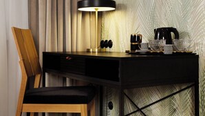 Une chambre moderne avec un bureau en bois, une chaise, une lampe et un mur orné d’un motif de feuilles de palmier.