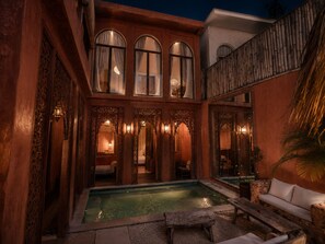 Ein Innenhof mit Pool, Holzarchitektur und einer Couch.