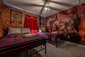 Een studentenkamer met twee bedden, een bakstenen muur en een groot muurschildering met het thema Hogwarts.