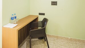 A room with a wooden desk, a chair, a water bottle, and a glass on the desk. - Lotus Leaf Guest House (Guwahati)