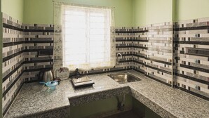 A kitchen with a window, a sink, a kettle, and a scale. - Lotus Leaf Guest House (Guwahati)