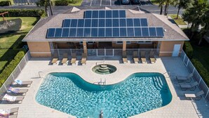 Un hotel con piscina, paneles solares en el techo y un patio cubierto.