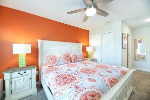Ein Schlafzimmer mit einem Bett, zwei Nachttischen, einem Deckenventilator und einer Tür.