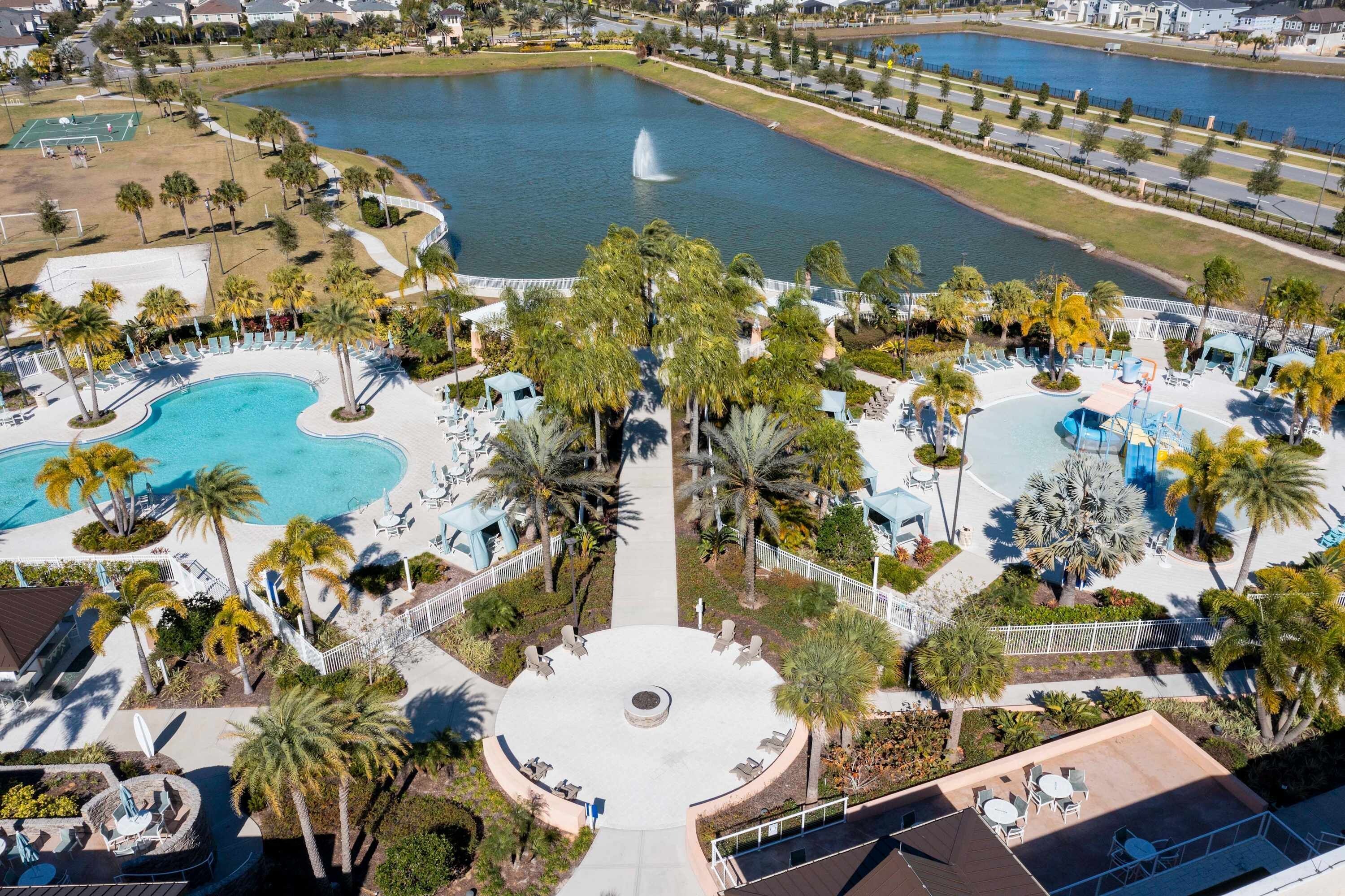 A resort with multiple swimming pools, palm trees, and a central fountain.