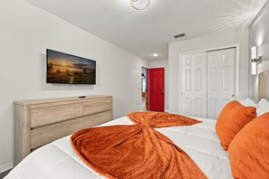 A bedroom with a bed, a TV mounted on the wall, a wooden dresser, and a red door. - Private Pool Oasis, Solara Resort,  Stylish Decor (Four Corners)