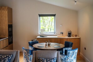A modern kitchen with a dining area, a window with a view, and a built-in oven. - Knockinaam Luxury Lodges (Stranraer)