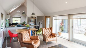 Un vaste espace de vie comprenant des fauteuils en cuir, une table à manger et une cuisine située à l’arrière-plan.
