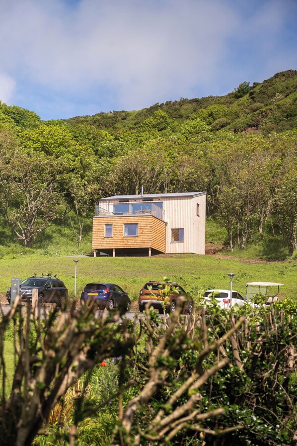 A modern two-story building with a flat roof, surrounded by lush greenery and parked cars. - Knockinaam Luxury Lodges (Stranraer)