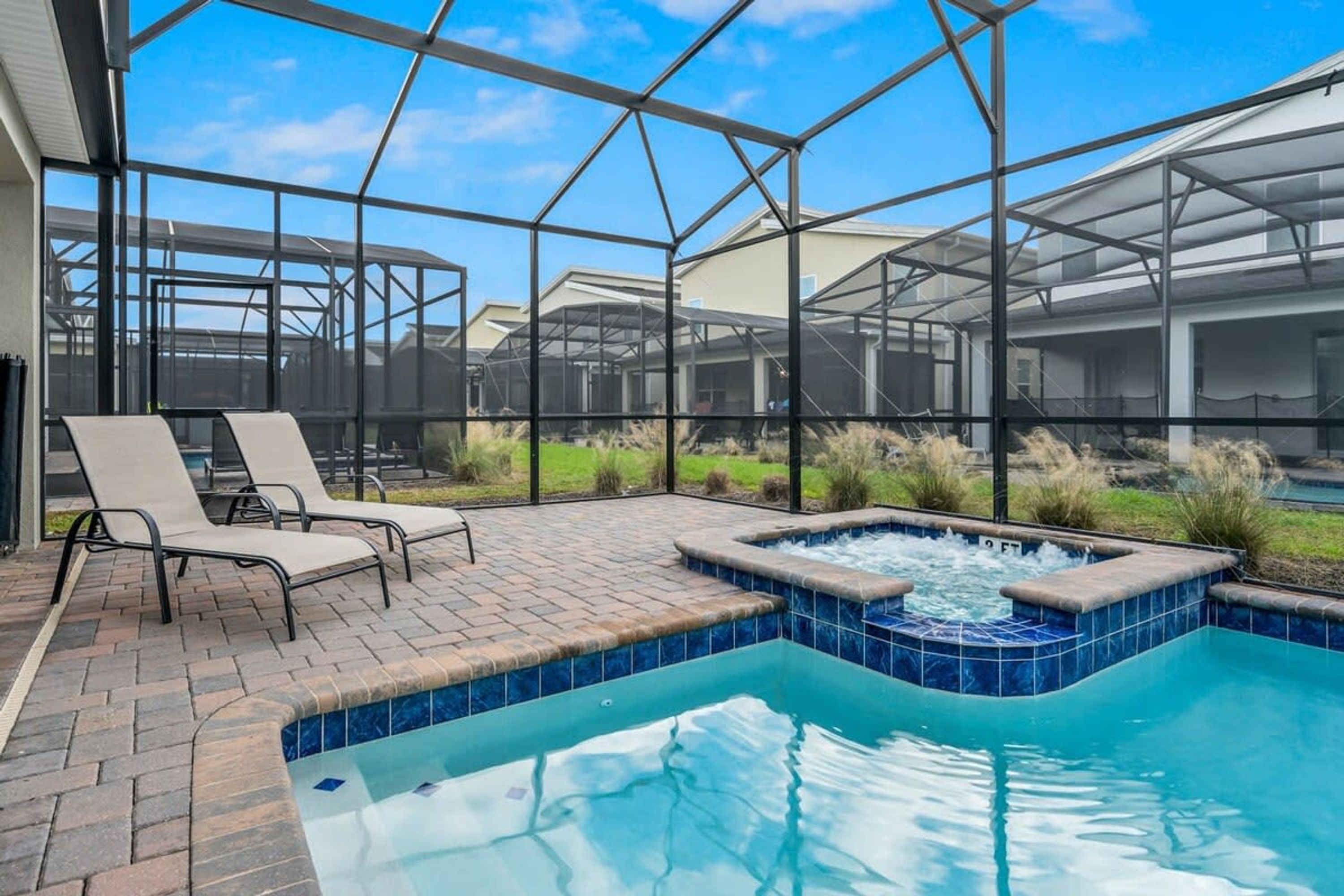 A pool area with lounge chairs, a hot tub, and a greenhouse structure.