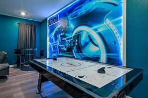 Ein Zimmer mit einem Shuffleboard-Tisch, einer Couch und einer Wandmalerei.