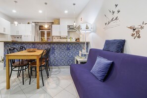 A modern kitchen with white cabinets, a blue patterned backsplash, and a dining area with a wooden table and chairs. - Family House in the Heart of Aveiro (Aveiro)