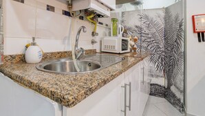 Una cocina con encimera de granito, pileta de acero inoxidable y microondas.
