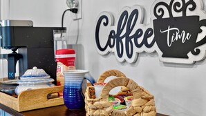 Una estación de café con una cafetera, una cesta de bollería y un cartel en la pared que dice 'Coffee time'.