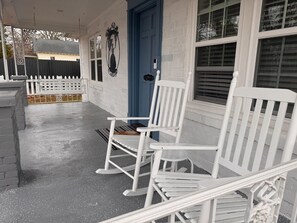 A porch with white rocking chairs, a blue door, and a white picket fence. - 2 bedrooms king/queen, sofa bed, fenced yard (Aiken)