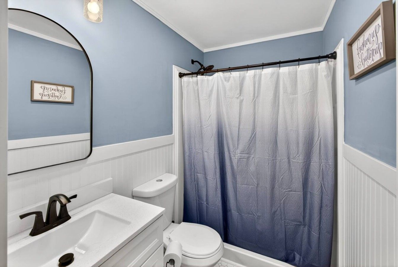 A bathroom with a white sink, toilet, and shower curtain.