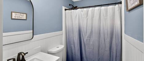 A bathroom with a white sink, toilet, and shower curtain.