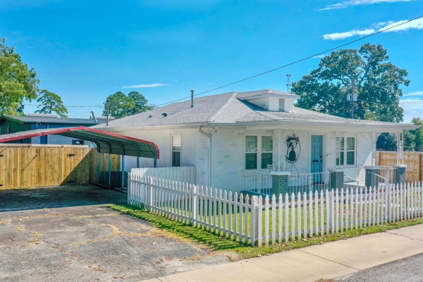 A single-story house with a white exterior, a covered porch, and a fenced yard.
