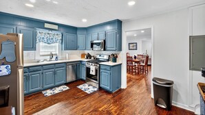 Una cocina con armarios azules, electrodomésticos de acero inoxidable y suelo de madera.