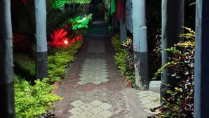 A pathway with a patterned pavement, flanked by greenery and a wooden structure overhead. - APAO VILLAGE & RESORT LODGE (Dar es Salaam)