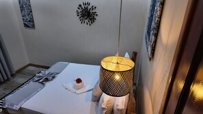 Un comedor ordenado con una mesa lista para dos personas, un adorno en la pared y una lámpara colgante.