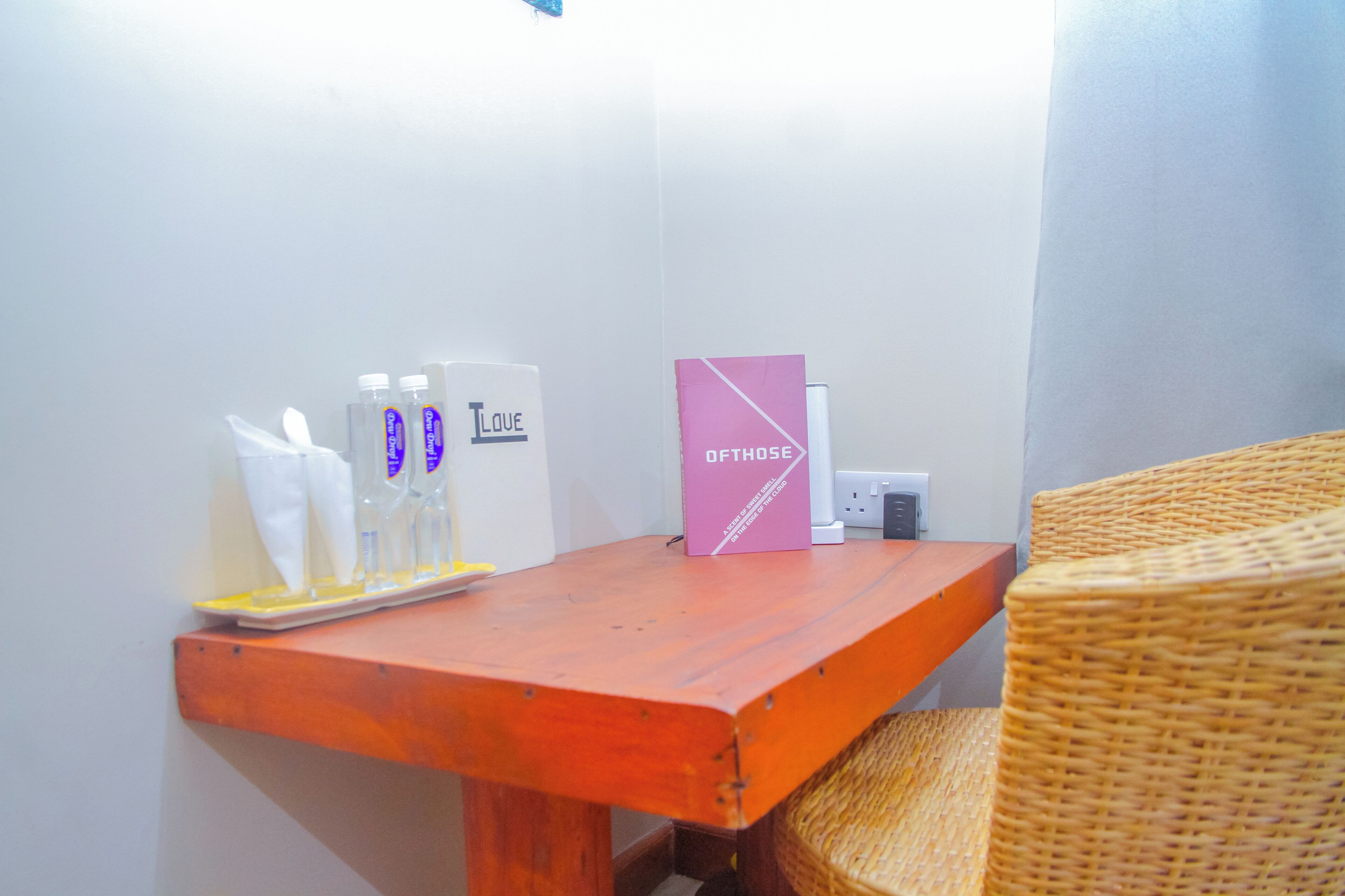 Een klein houten tafeltje met een mandje, een roze doosje en wat toiletartikelen.