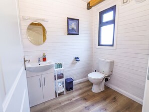 Ein kleines Badezimmer mit einem weißen Waschbecken, einer Toilette und einem kleinen Fenster.