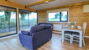 Un espace de vie et de salle à manger moderne, à aire ouverte, avec un plafond en bois, de grandes fenêtres et un canapé gris.