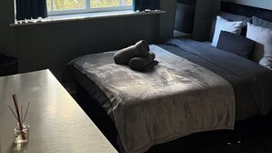 Ein Schlafzimmer mit einem Bett, einem Nachttisch und einem Fenster mit Vorhängen.
