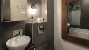 Ein modernes Badezimmer mit großem Spiegel, einem Aufsatzwaschbecken, Toilette und Duschbereich.