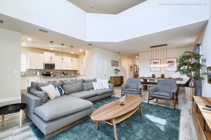 A spacious living area with a sectional sofa, a wooden coffee table, and a dining table with chairs. - Chic Home, Themed Bedrooms, Game Room, Best Spot (Kissimmee)