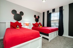 A hotel room with two beds, each with red bedding and Mickey Mouse headboards. - Storey Lake Home, Mickey & Minions Beds, Sleeps 12 (Kissimmee)