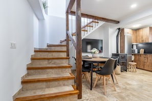Un escalier menant à une salle à manger avec une table et des chaises, une cuisine dotée de meubles en bois et une grande fenêtre.