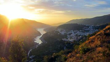 Een rivierdal met een stadje, bergen en een zonsondergang.