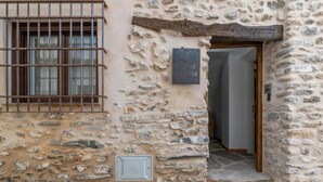 A stone building with a barred window, a door, and a small step leading to the entrance.