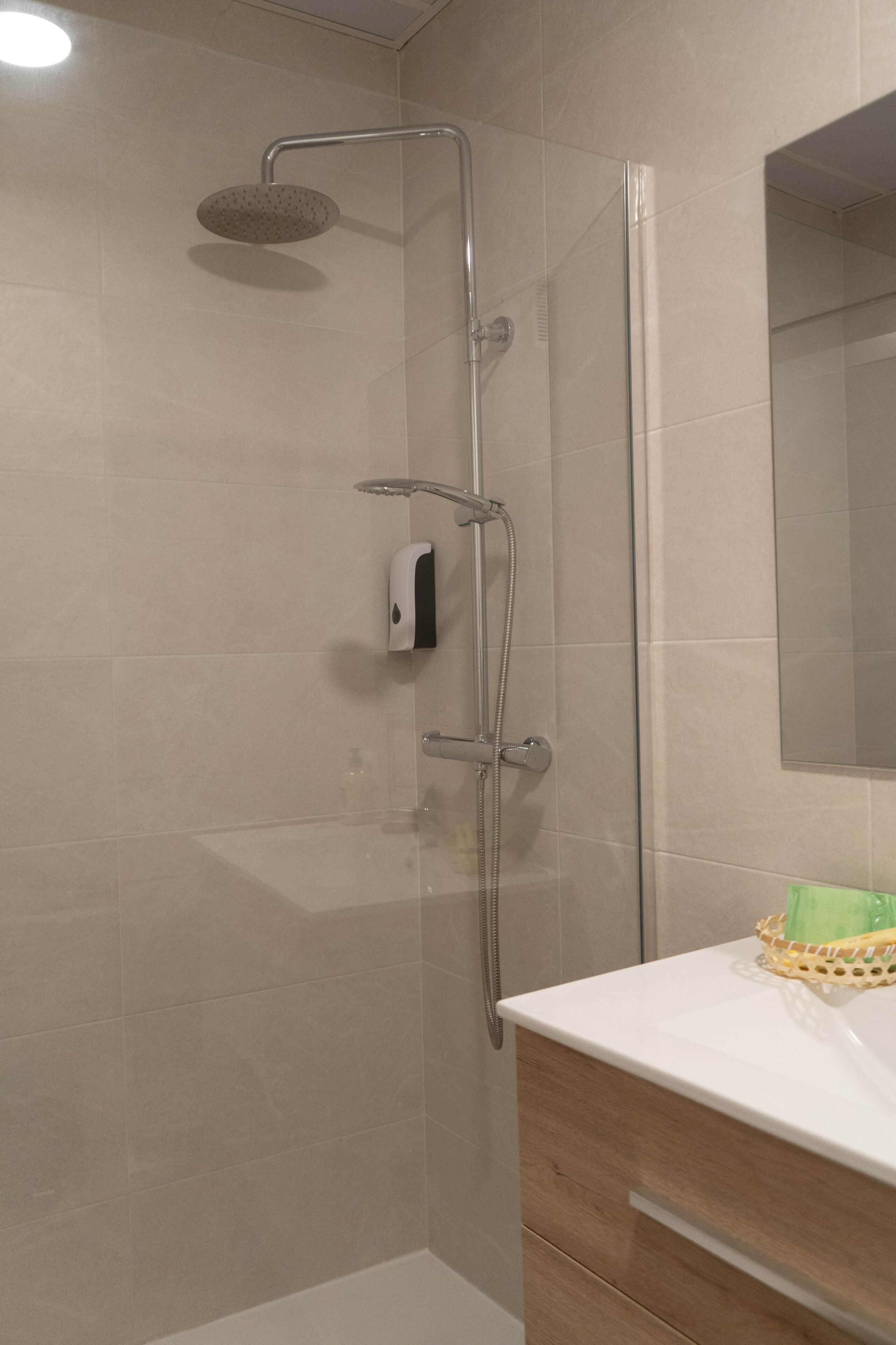 Une douche équipée d’un pommeau de douche à main, d’un autre pommeau de douche à main et d’un pommeau de douche fixé au mur.