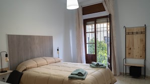 Ein Schlafzimmer mit einem Bett, einem Schreibtisch, einem Stuhl, einem Fenster mit Vorhängen und einem Holzregal.