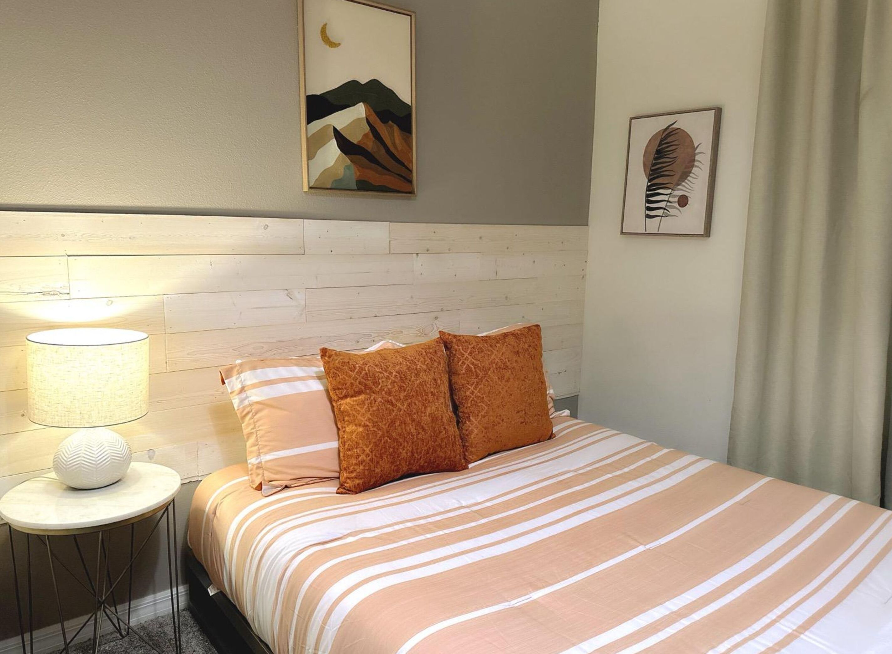 A neatly made bed with striped bedding, a bedside lamp, and two pillows.