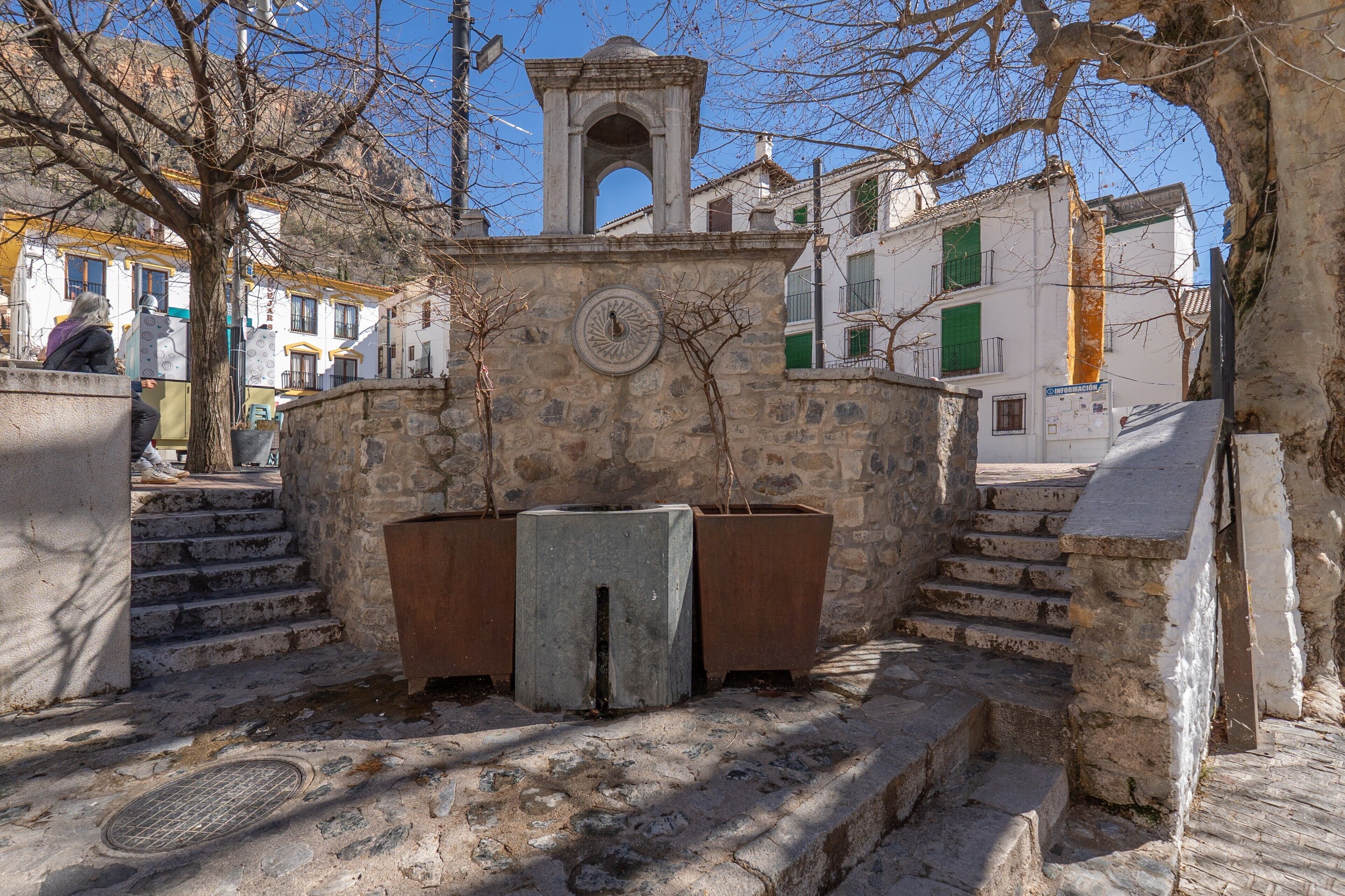 Una escala de pedra que condueix a una torre campanar, envoltada d'edificis amb balcons i finestres.